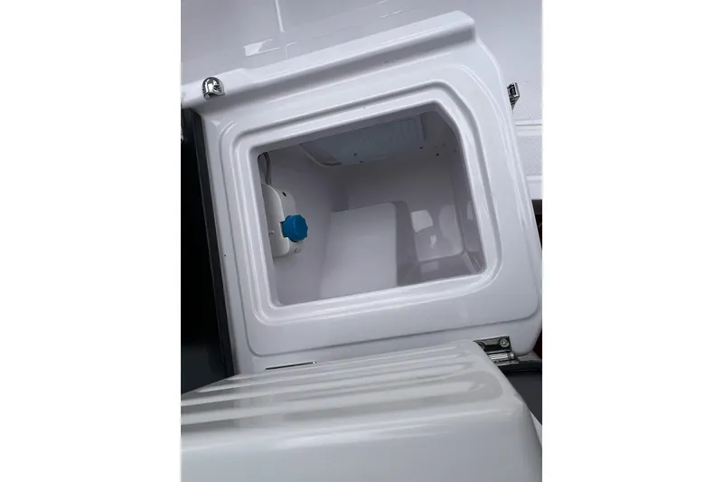 Slide: The Image of Open storage compartment on 2025 Axopar Sun-Top boat, featuring a white interior. - 35