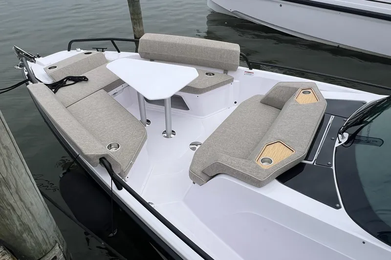 Slide: The Image of 2025 Axopar Sun-Top boat with beige seating and a white table, docked on calm water. - 40