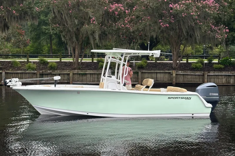 Slide: The Image of 2021 Sportsman Heritage 231 Center Console boat on calm water, surrounded by lush greenery. - 18