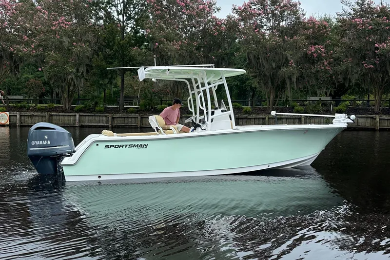 Slide: The Image of 2021 Sportsman Heritage 231 Center Console boat on calm water, surrounded by trees. - 21