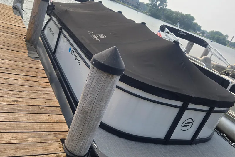 The Image of 2022 Flagship Pontoon E22CU docked with black cover, wooden pier in foreground. - 0