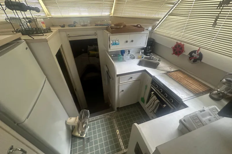 Slide: The Image of 1971 Chris-Craft Commander 42 kitchen with stove, sink, and refrigerator, featuring nautical decor. - 57