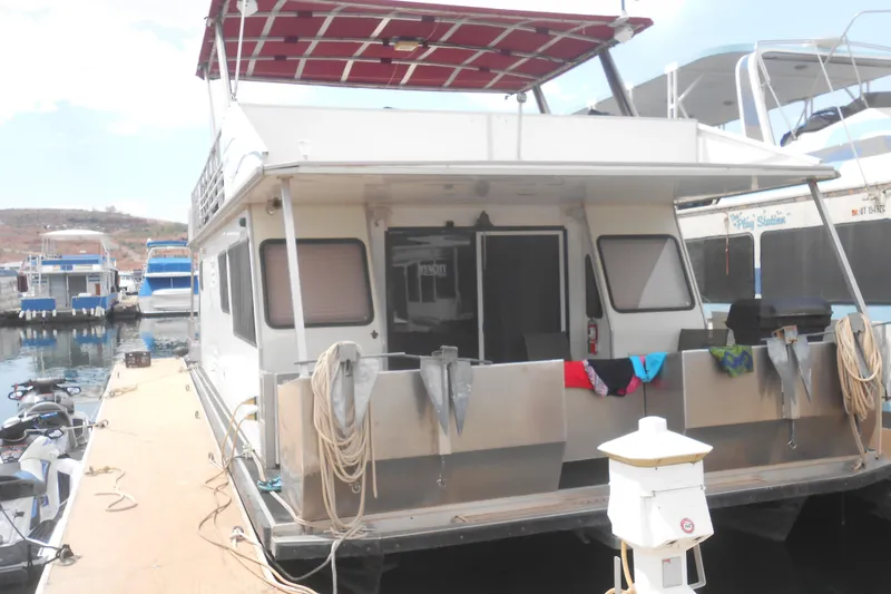 Slide: The Image of 2004 Myacht 4815 houseboat docked at marina with red canopy and mooring ropes. - 1