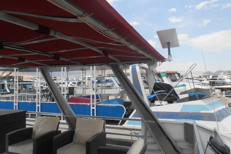 Slide: The Image of 2004 Myacht 4815 houseboat with red canopy, docked among other boats under a blue sky. - 19