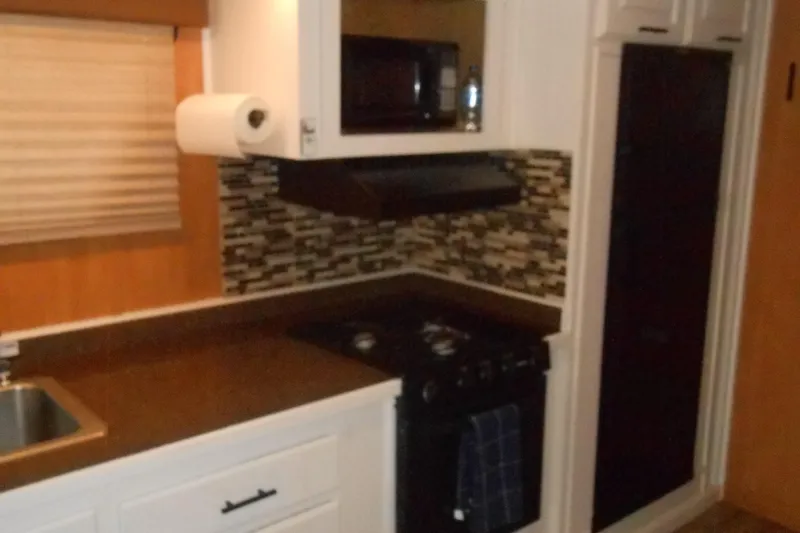 Slide: The Image of Compact kitchen in a 2004 Myacht 4815, featuring stove, microwave, and modern backsplash. - 4