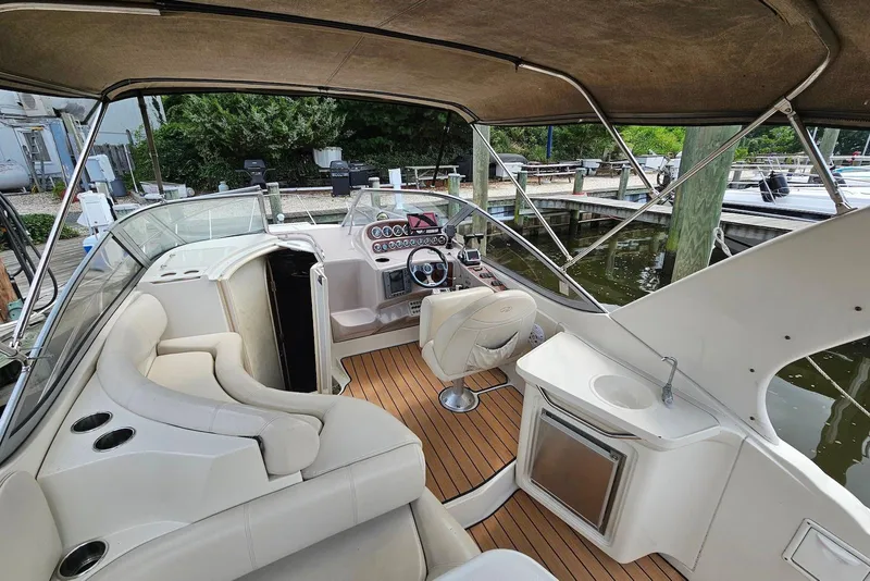 Slide: The Image of 1999 Regal Commodore 292 boat interior with seating, helm, and kitchenette at a marina. - 10