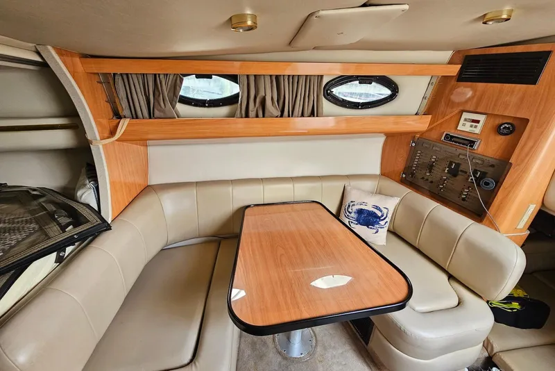 Slide: The Image of Interior of 1999 Regal Commodore 292 boat with beige seating and wooden table. - 23