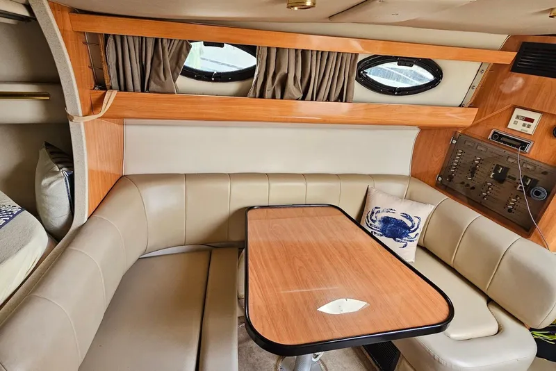 Slide: The Image of Interior of 1999 Regal Commodore 292 boat with cozy seating and wooden table. - 24