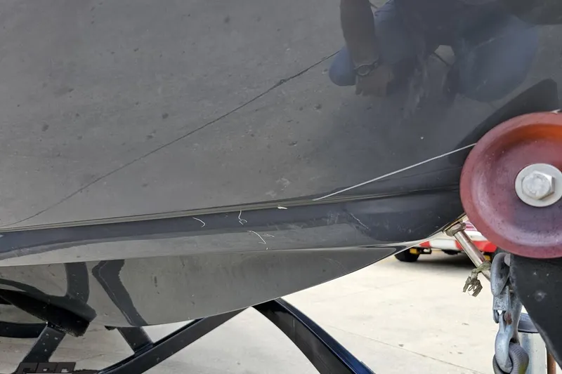 Slide: The Image of 2014 Moomba Outback V boat hull with visible scratches and trailer attachment. - 13