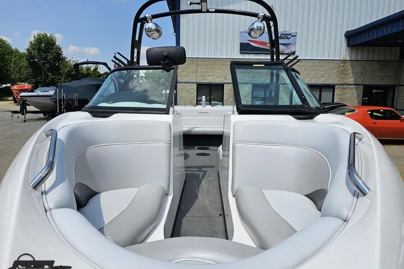 Slide: The Image of 2014 Moomba Outback V boat interior with white seating and windshield, parked outdoors. - 15