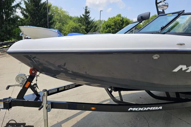 Slide: The Image of 2014 Moomba Outback V boat on trailer, parked outdoors with trees in background. - 17