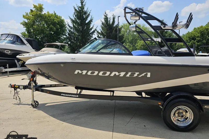 Slide: The Image of 2014 Moomba Outback V boat on trailer, parked outdoors under a clear sky. - 21
