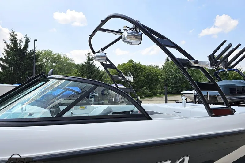 Slide: The Image of 2014 Moomba Outback V boat with wakeboard tower, parked outdoors under a clear sky. - 25