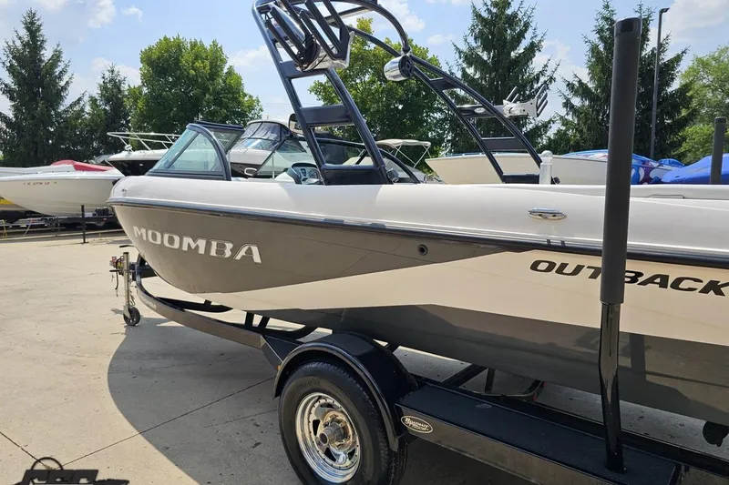 Slide: The Image of 2014 Moomba Outback V boat on trailer, parked outdoors with trees in background. - 28