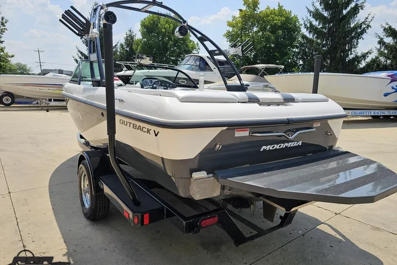 Slide: The Image of 2014 Moomba Outback V boat on trailer, parked outdoors with other boats nearby. - 29