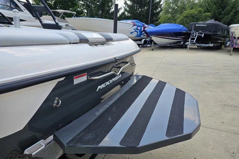 Slide: The Image of 2014 Moomba Outback V boat with swim platform, parked among other boats. - 34