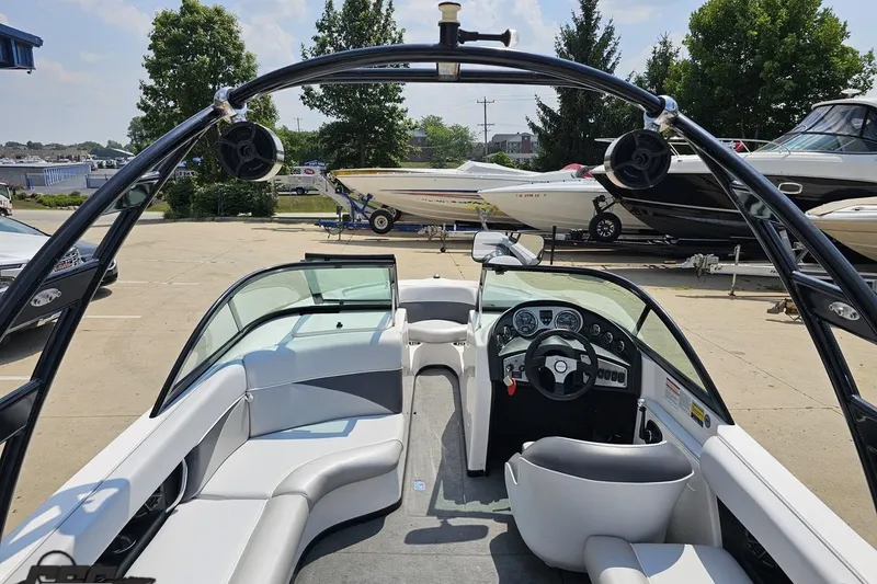 Slide: The Image of 2014 Moomba Outback V boat interior with seating and dashboard, parked outdoors. - 42