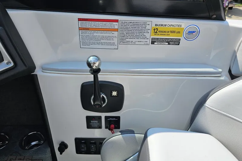 Slide: The Image of 2014 Moomba Outback V boat dashboard with control lever and capacity warning labels. - 58