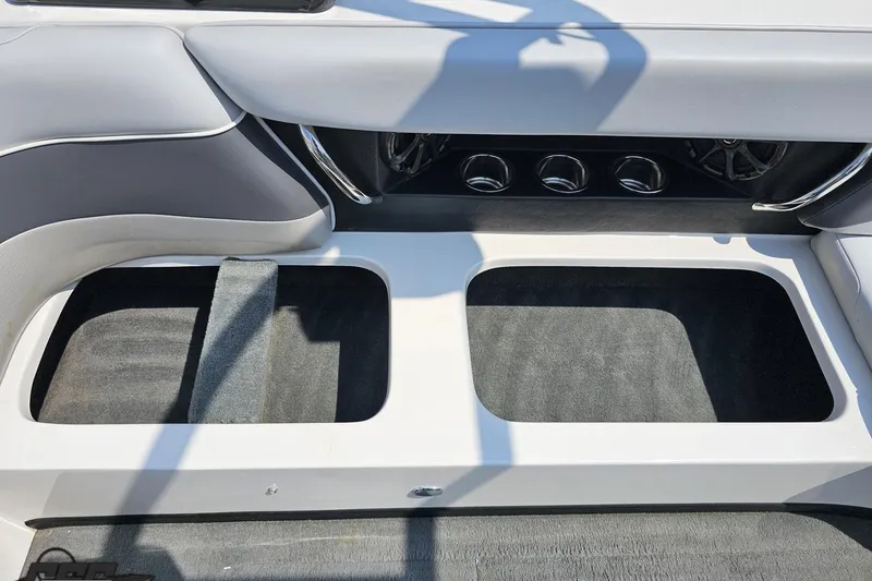 Slide: The Image of 2014 Moomba Outback V interior storage compartments with gray upholstery and cup holders. - 84