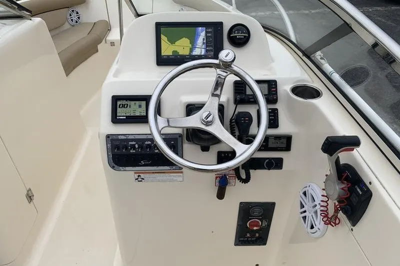 Slide: The Image of 2018 Scout 225 Dorado boat dashboard with steering wheel and navigation controls. - 16