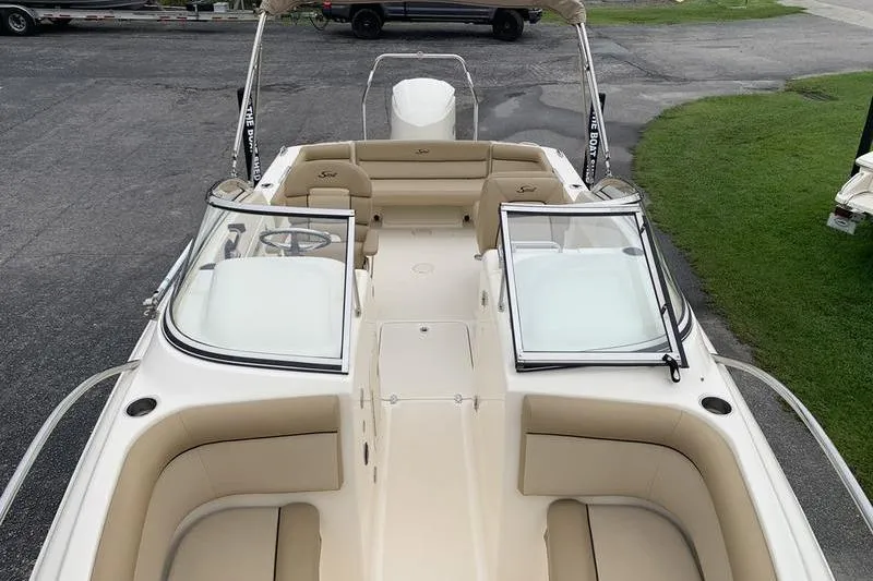 Slide: The Image of 2018 Scout 225 Dorado boat with beige seating and open windshield, parked on pavement. - 26
