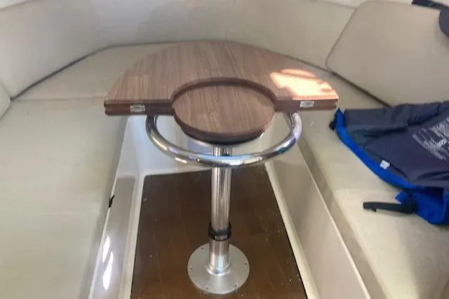 Slide: The Image of 2016 Boston Whaler 315 Conquest cabin interior with wooden table and cushioned seating. - 7