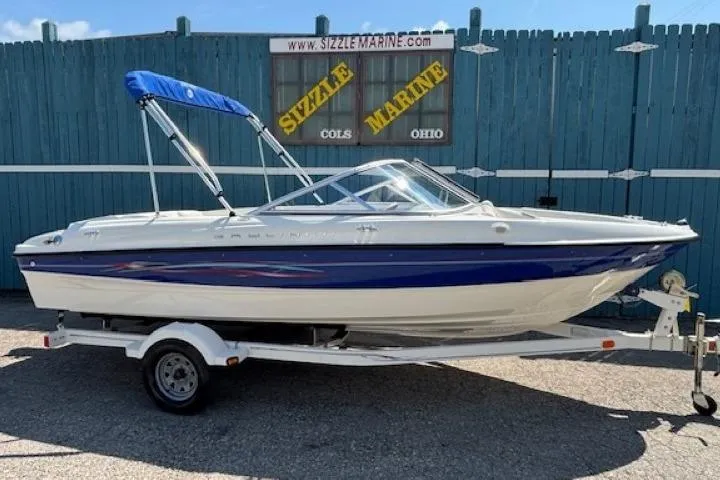 The Image of 2006 Bayliner 185 Bowrider boat with blue accents on a trailer, parked outdoors. - 0