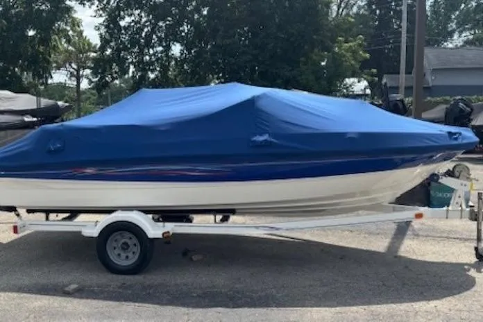 Slide: The Image of 2006 Bayliner 185 Bowrider boat with blue cover on trailer, parked outdoors. - 28