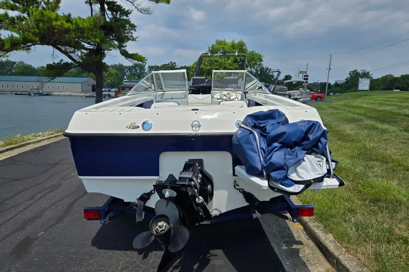 Slide: The Image of 2006 Bayliner 195 Classic boat parked near a lake, showcasing its rear view and propeller. - 2