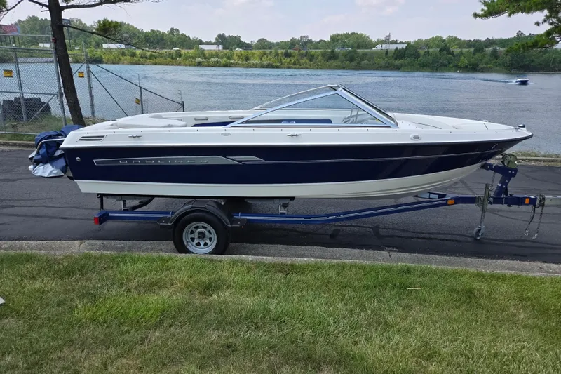 Slide: The Image of 2006 Bayliner 195 Classic boat on trailer by a lakeside road. - 9