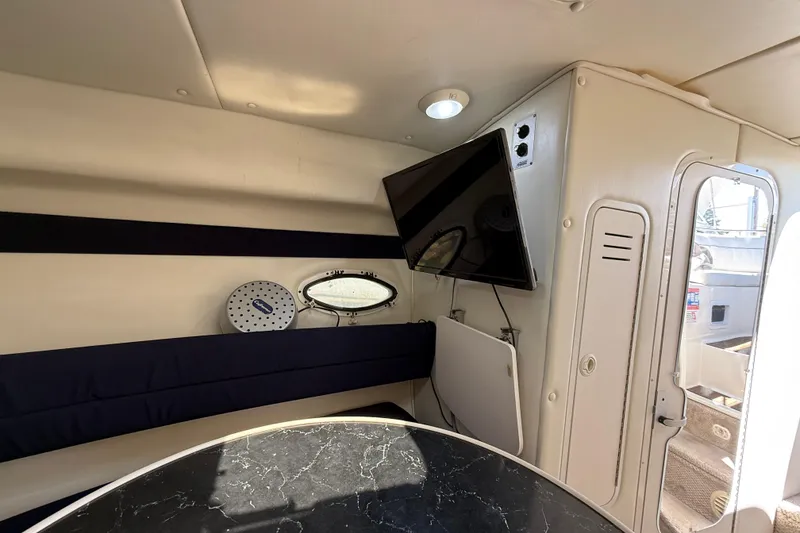 Slide: The Image of Interior of 2000 Rinker 270 Fiesta Vee boat with TV and seating area. - 18