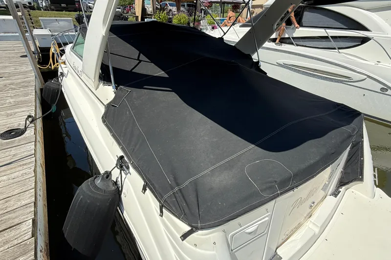 Slide: The Image of 2000 Rinker 270 Fiesta Vee boat docked with black cover, side view. - 2