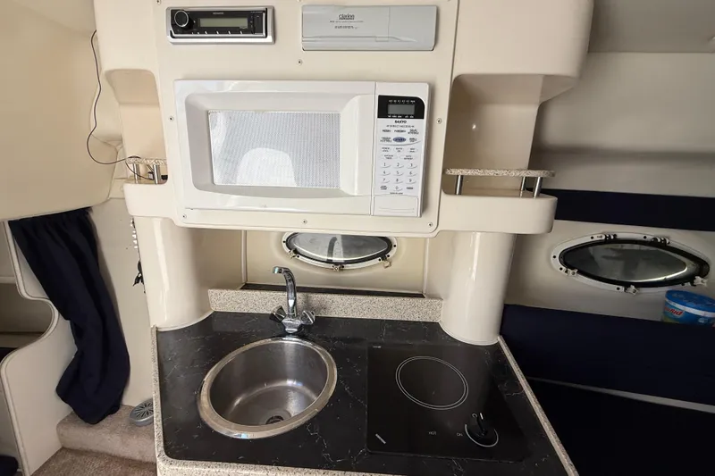 Slide: The Image of Compact kitchen in 2000 Rinker 270 Fiesta Vee boat with sink, microwave, and stove. - 23