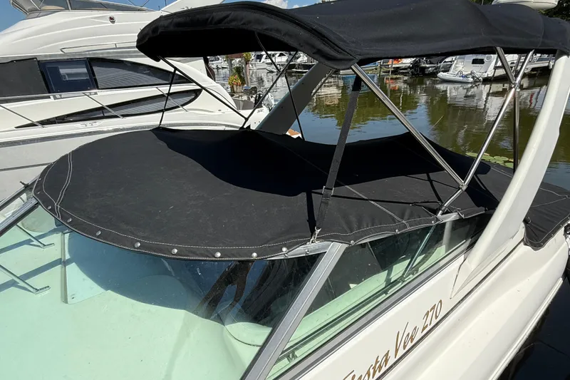 Slide: The Image of 2000 Rinker 270 Fiesta Vee boat with black canopy docked at marina. - 3