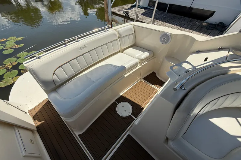 Slide: The Image of 2000 Rinker 270 Fiesta Vee boat interior with white seating and wood flooring. - 9