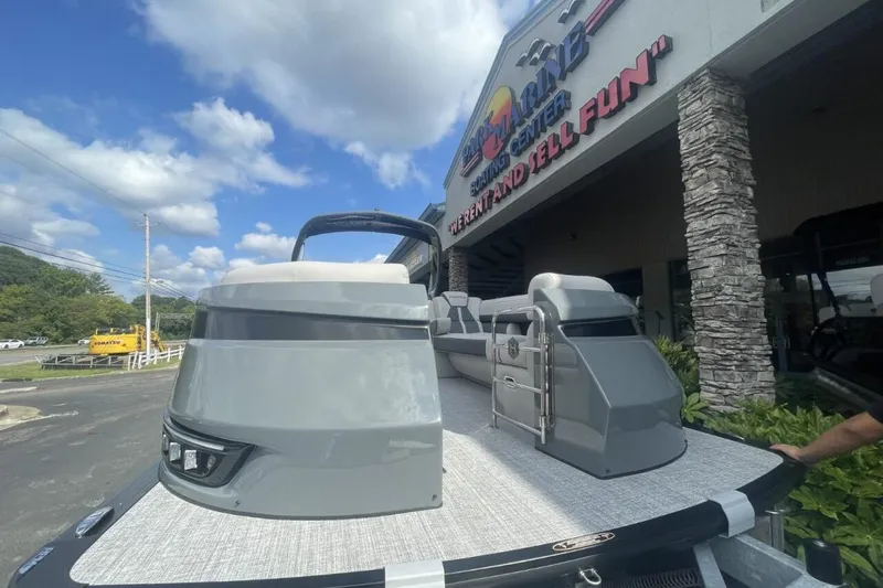 Slide: The Image of 2026 Harris Grand Mariner 250 pontoon boat displayed at a boating center under a blue sky. - 1