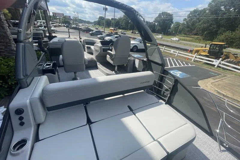 Slide: The Image of 2026 Harris Grand Mariner 250 pontoon boat interior with seating and helm, parked outdoors. - 9