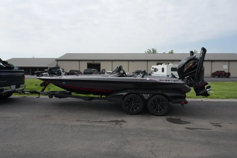 The Image of 2025 Skeeter FXR20 LE boat on trailer, parked outdoors near industrial buildings. - 1