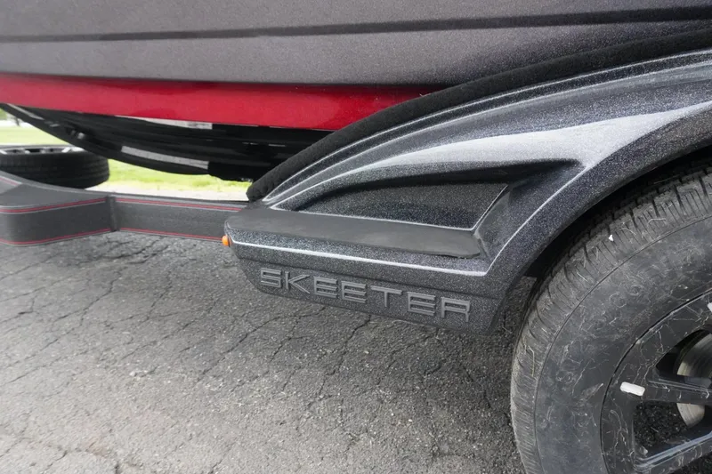 Slide: The Image of 2025 Skeeter FXR20 LE boat trailer with detailed branding and tire on asphalt. - 3