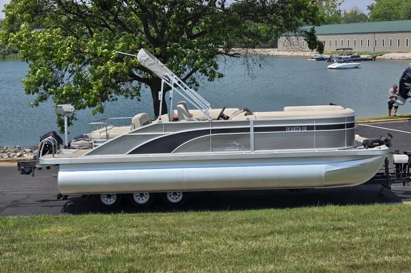 Slide: The Image of 2019 Bennington SX 22 Premium Cruise pontoon boat on trailer by a lake. - 0
