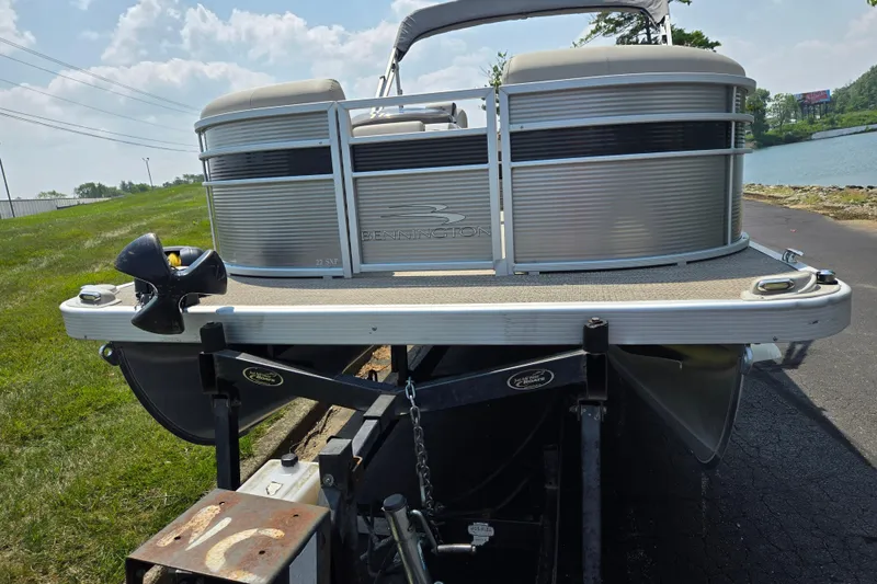 Slide: The Image of 2019 Bennington SX 22 Premium Cruise pontoon boat on trailer by a lake. - 6