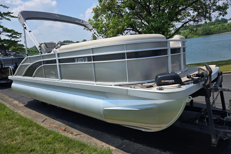 Slide: The Image of 2019 Bennington SX 22 Premium Cruise pontoon boat on trailer by a lake. - 8