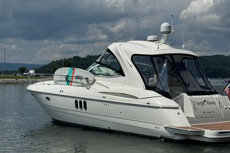 Slide: The Image of 2007 Cruisers Yachts 420 Express on water, overcast sky, docked with surfboard. - 3