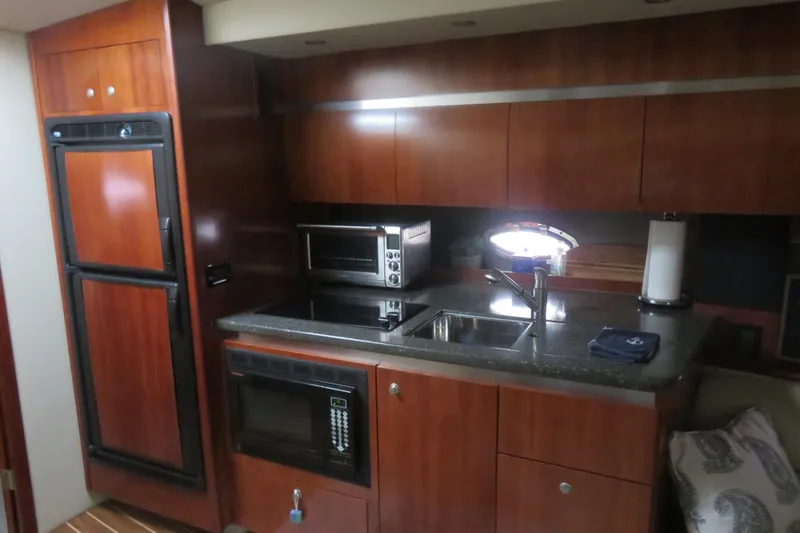 Slide: The Image of 2007 Cruisers Yachts 420 Express kitchen with wood cabinetry, sink, and appliances. - 9