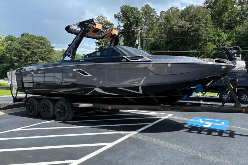 Slide: The Image of 2021 Centurion Ri265 boat on trailer in parking lot, surrounded by trees. - 3