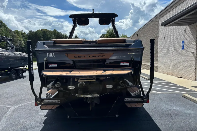 Slide: The Image of 2021 Centurion Ri265 boat rear view in parking lot, showcasing sleek design and features. - 4