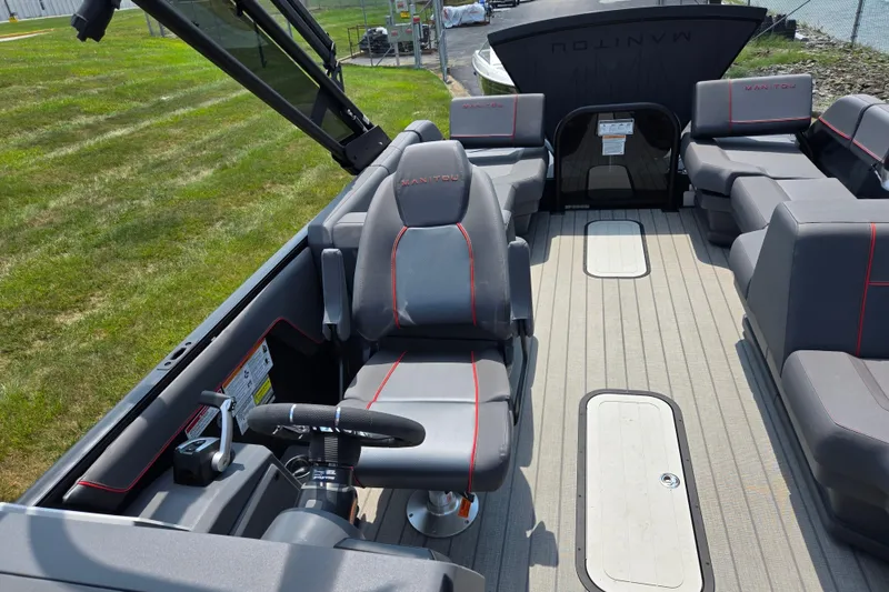 Slide: The Image of 2024 Manitou Explore boat interior with gray seating and modern steering console. - 12