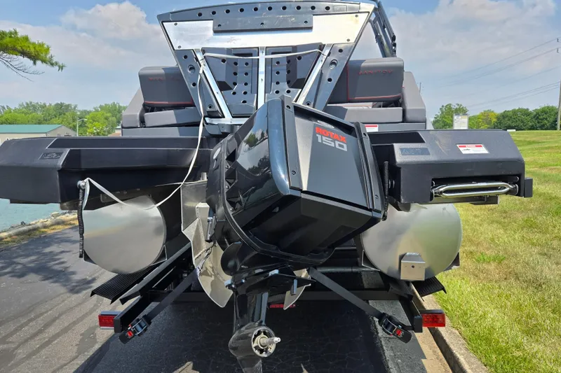 Slide: The Image of 2024 Manitou Explore boat with Rotax 150 engine, parked on a sunny day. - 2
