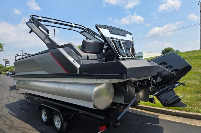 Slide: The Image of 2024 Manitou Explore pontoon boat on trailer, featuring sleek design and modern outboard motor. - 3