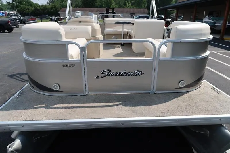 Slide: The Image of 2012 Sweetwater 200 Classic pontoon boat with beige seating, parked in a lot. - 8